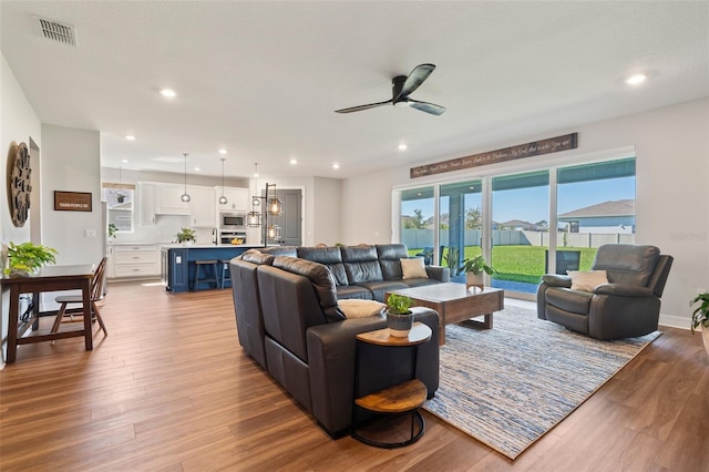 living room with recessed lighting, visible vents, a ceiling fan, wood finished floors, and baseboards