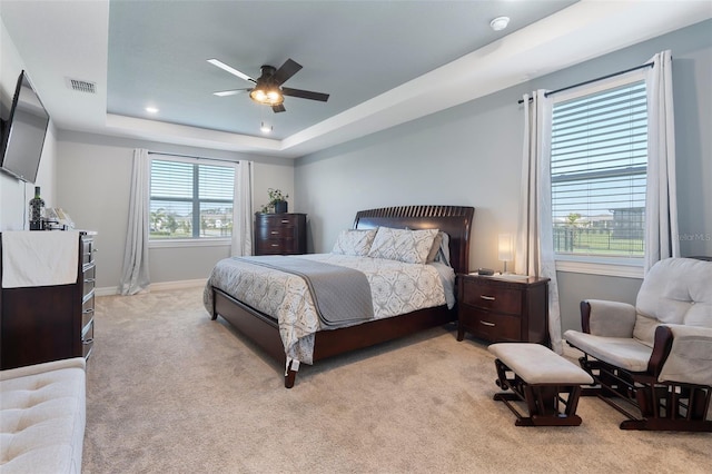 bedroom featuring a tray ceiling, carpet, visible vents, ceiling fan, and baseboards