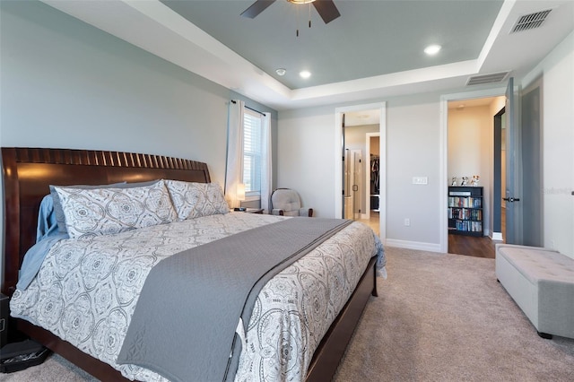 carpeted bedroom with baseboards, visible vents, ceiling fan, and a tray ceiling