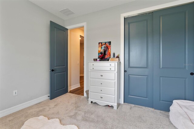 carpeted bedroom featuring baseboards, visible vents, and a closet