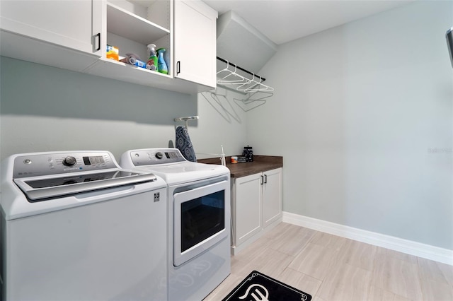 laundry room with cabinet space, baseboards, and washer and clothes dryer