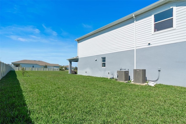 view of home's exterior featuring central AC, a lawn, fence, and stucco siding