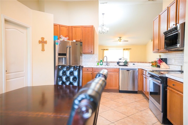 kitchen featuring light tile patterned floors, a sink, light countertops, appliances with stainless steel finishes, and decorative backsplash