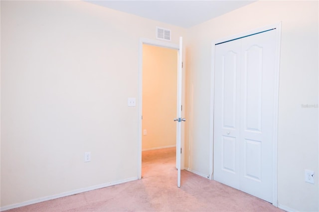 unfurnished bedroom featuring baseboards, a closet, visible vents, and light colored carpet