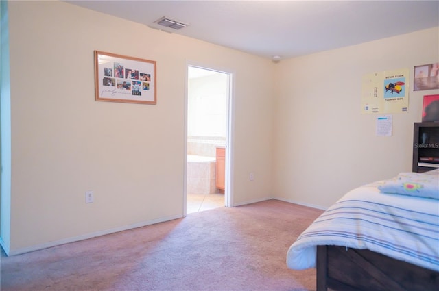 bedroom featuring ensuite bath, carpet flooring, visible vents, and baseboards