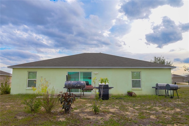 rear view of property with roof with shingles and stucco siding