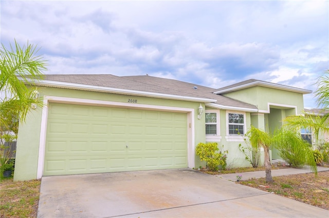 single story home with a garage, a shingled roof, concrete driveway, and stucco siding