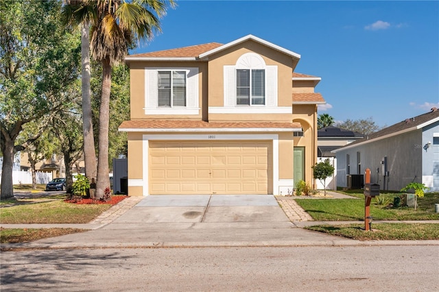 traditional home featuring central air condition unit, stucco siding, concrete driveway, an attached garage, and a front yard