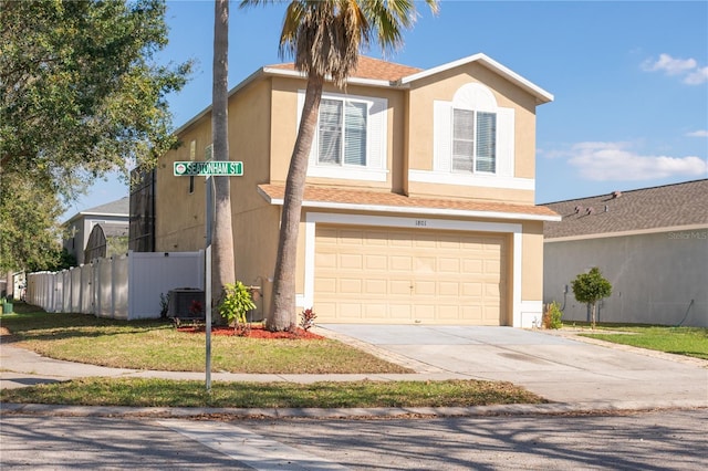 traditional-style house featuring concrete driveway, fence, and stucco siding