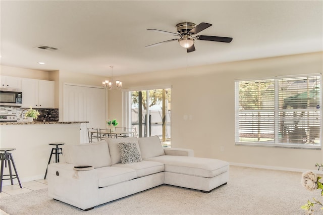 living room with ceiling fan with notable chandelier, visible vents, and baseboards