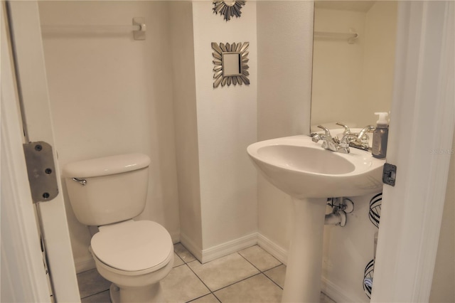 half bathroom with toilet, baseboards, and tile patterned floors