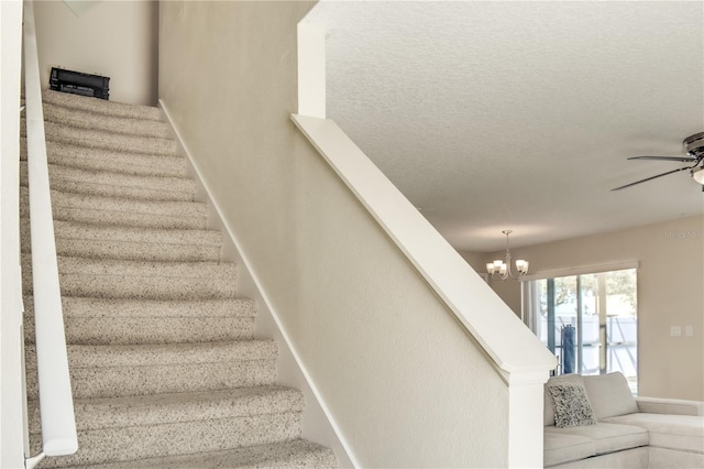 stairs with ceiling fan with notable chandelier