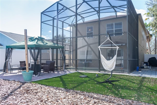 rear view of property featuring glass enclosure, a patio area, fence, and a yard