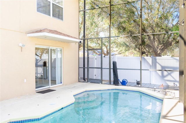 view of swimming pool featuring glass enclosure, a patio area, fence, and a fenced in pool