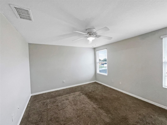 unfurnished room featuring ceiling fan, baseboards, visible vents, and dark colored carpet