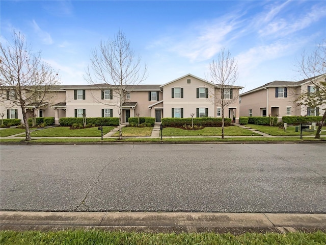 multi unit property with a front lawn and stucco siding