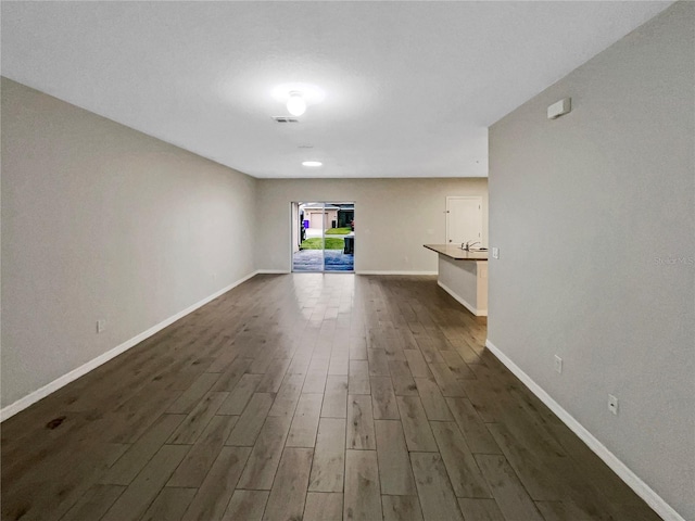 unfurnished living room featuring dark wood finished floors, visible vents, and baseboards