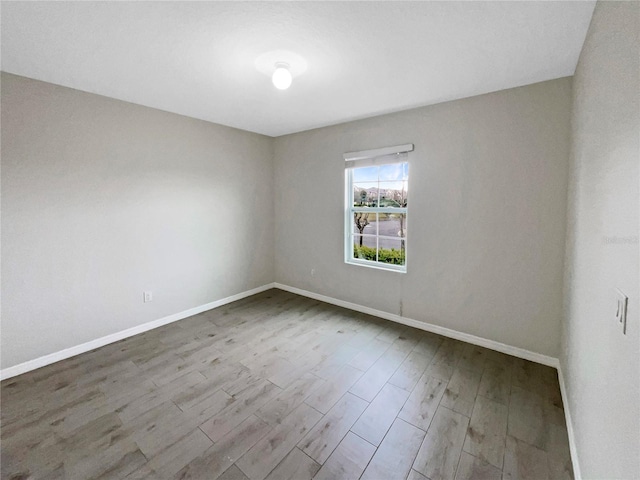 spare room featuring baseboards and wood finished floors