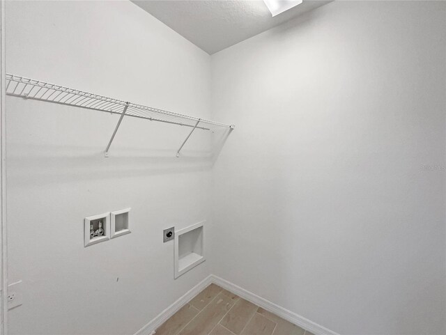 clothes washing area with hookup for a washing machine, wood tiled floor, hookup for an electric dryer, laundry area, and baseboards