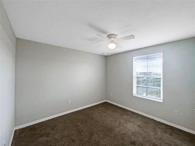 empty room featuring ceiling fan, baseboards, and dark colored carpet