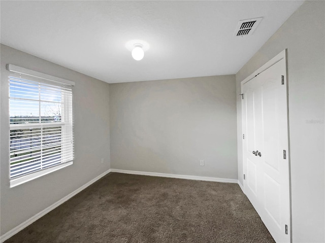 unfurnished bedroom featuring visible vents, dark carpet, and baseboards