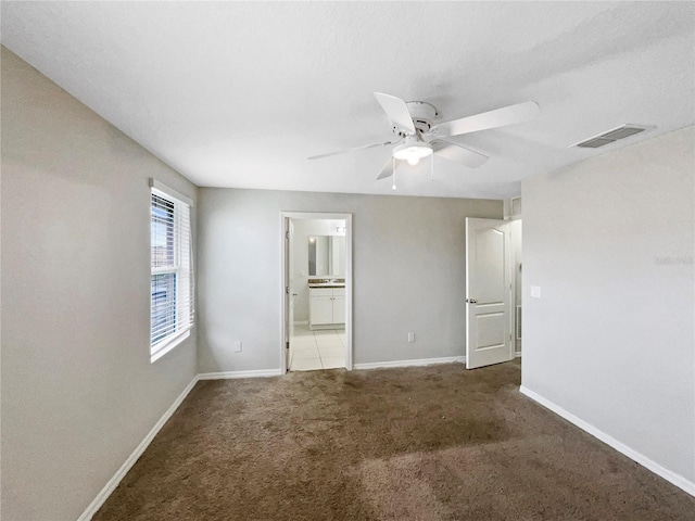 unfurnished bedroom with carpet floors, visible vents, baseboards, and ensuite bathroom