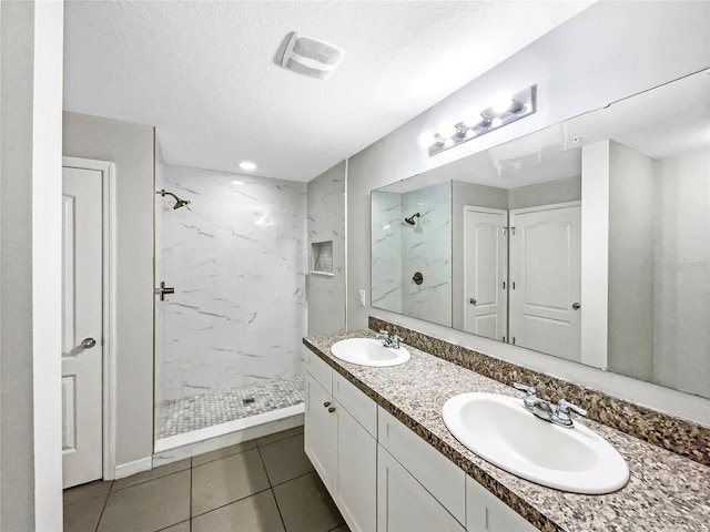 full bathroom featuring visible vents, a textured ceiling, a sink, and a marble finish shower