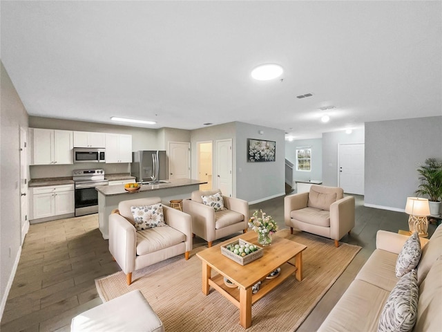 living room with light wood-style flooring, visible vents, and baseboards