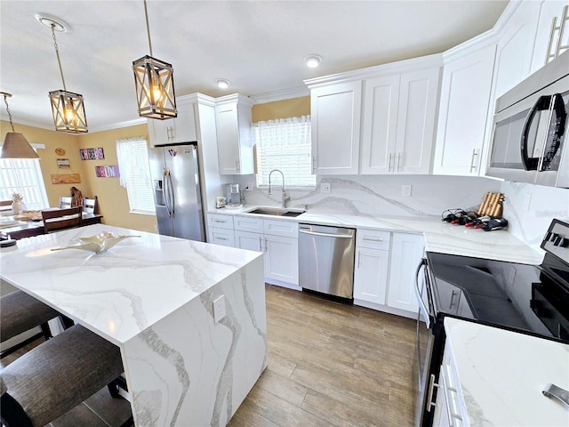 kitchen with stainless steel appliances, ornamental molding, a sink, and white cabinetry