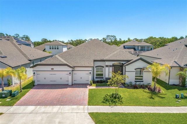 view of front of property featuring a front lawn, an attached garage, a shingled roof, stucco siding, and decorative driveway