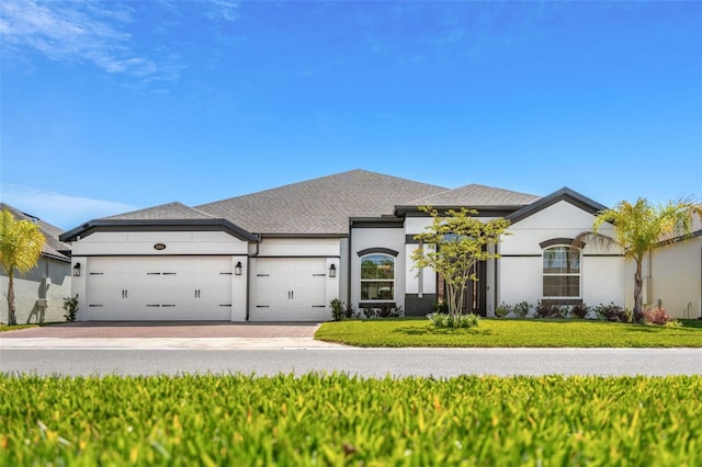 view of front of home with an attached garage, driveway, a front yard, and stucco siding