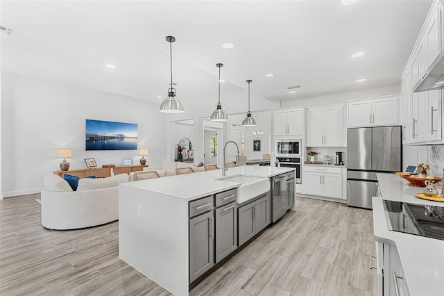 kitchen featuring appliances with stainless steel finishes, a sink, white cabinetry, and light countertops