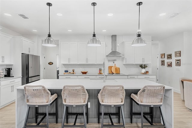 kitchen featuring wall chimney exhaust hood, freestanding refrigerator, and tasteful backsplash