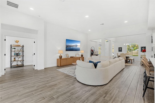 living area featuring baseboards, light wood-style flooring, visible vents, and recessed lighting