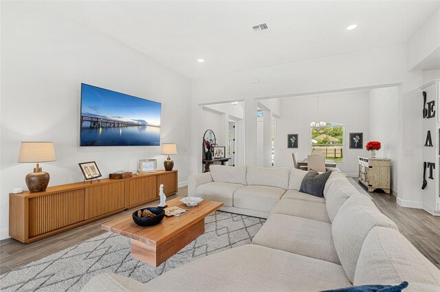 living area featuring an inviting chandelier, light wood finished floors, baseboards, visible vents, and recessed lighting