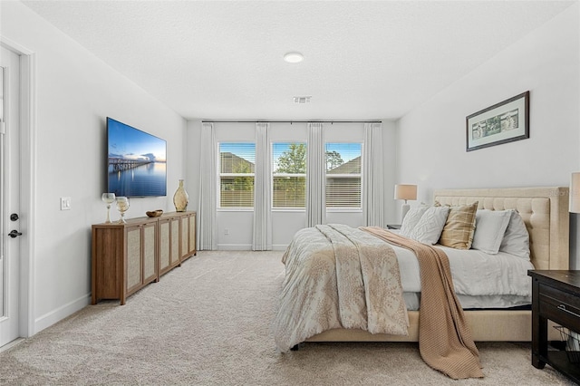 bedroom with baseboards, visible vents, and light carpet