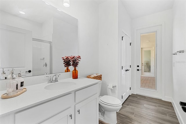 full bath with wood finished floors, toilet, vanity, baseboards, and a stall shower