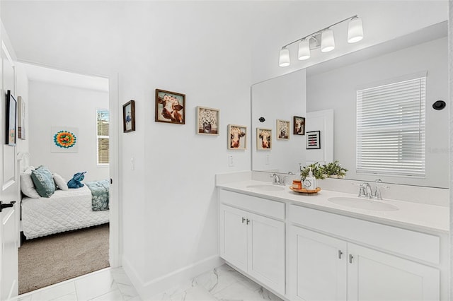 ensuite bathroom featuring connected bathroom, marble finish floor, baseboards, and a sink