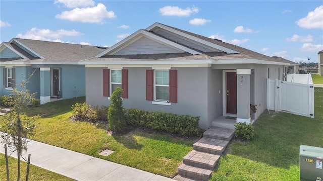 view of front of home with a front lawn, fence, a gate, and stucco siding