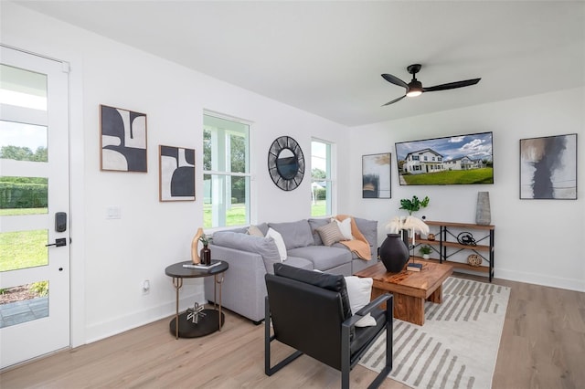 living area featuring light wood-style floors, baseboards, and a ceiling fan