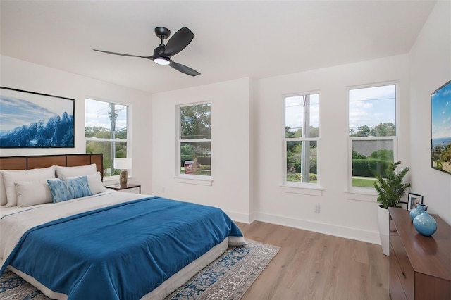 bedroom featuring light wood-type flooring, baseboards, and a ceiling fan