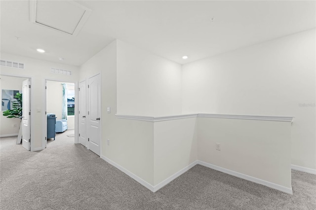 hall featuring baseboards, carpet, visible vents, and attic access