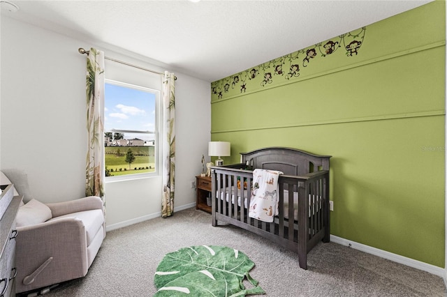 carpeted bedroom featuring a nursery area and baseboards