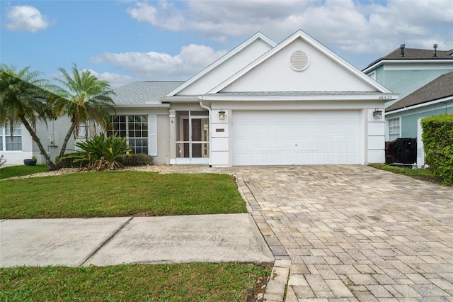 ranch-style house featuring a front lawn, decorative driveway, an attached garage, and stucco siding