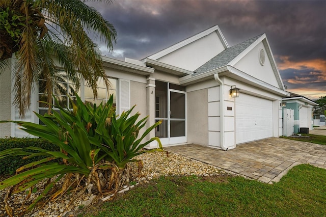 exterior space featuring a garage, decorative driveway, and stucco siding