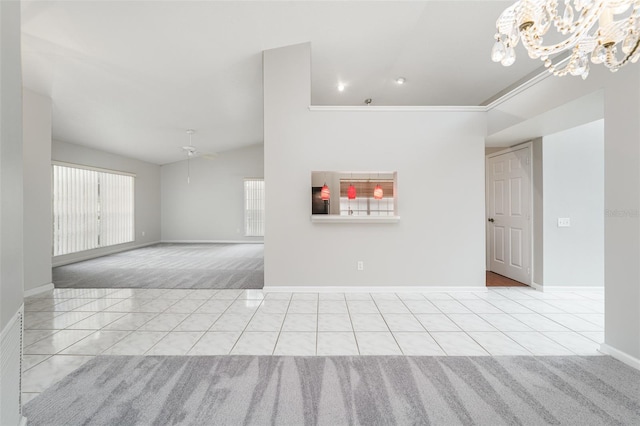 spare room featuring lofted ceiling, baseboards, a wealth of natural light, and tile patterned floors