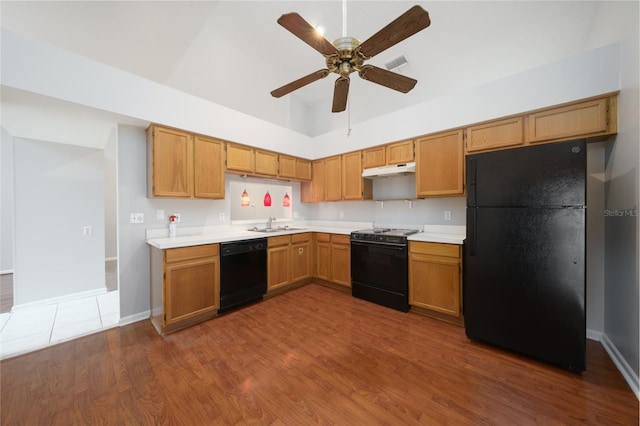 kitchen with dark wood-style floors, light countertops, visible vents, under cabinet range hood, and black appliances