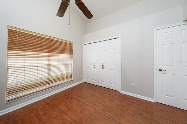 unfurnished bedroom with a closet, vaulted ceiling, baseboards, and wood finished floors