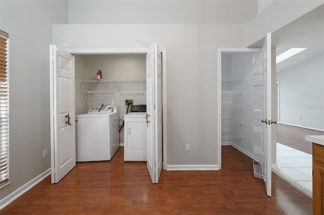 washroom with laundry area, washer and clothes dryer, wood finished floors, and baseboards