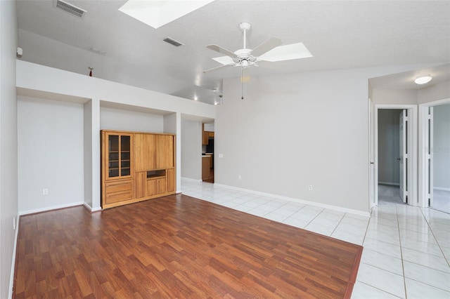 unfurnished living room featuring ceiling fan, visible vents, baseboards, and light tile patterned flooring